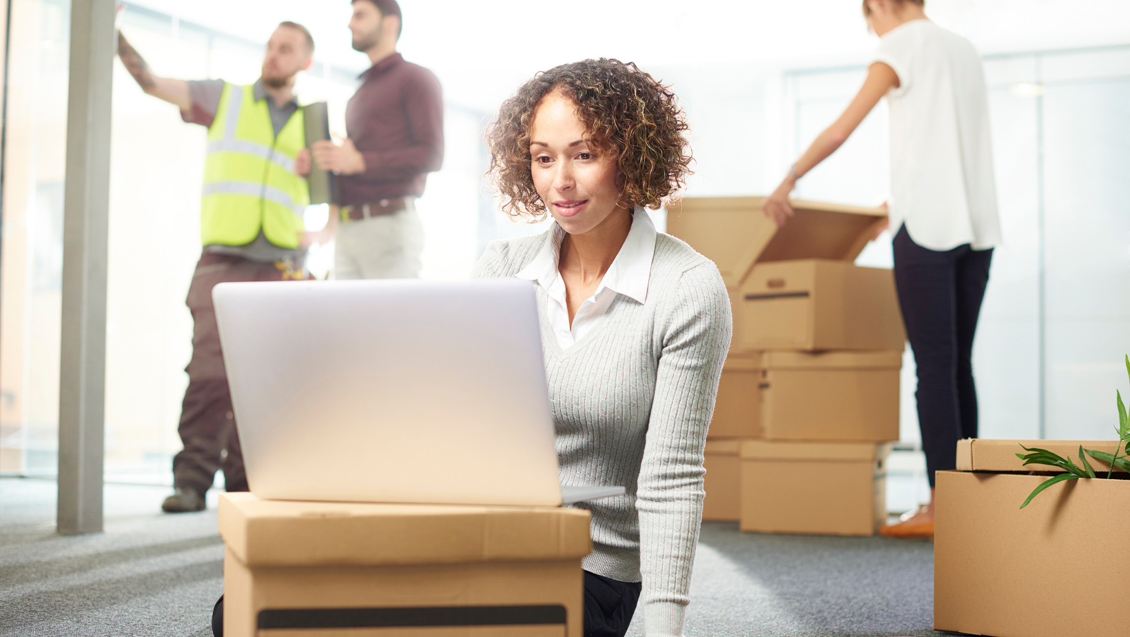 woman looking at laptop on a box during an office move
