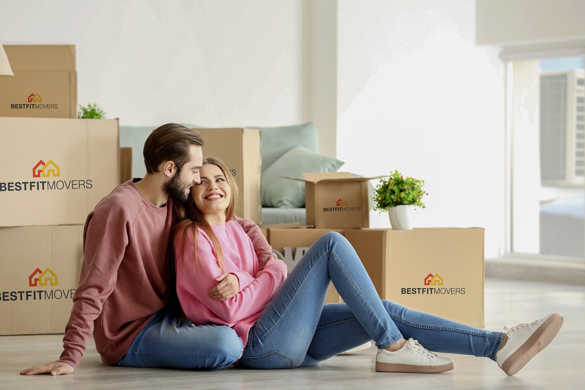 couple leaning against moving boxes while smiling