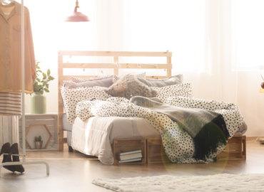 studio apartment with clothes rack next to bed