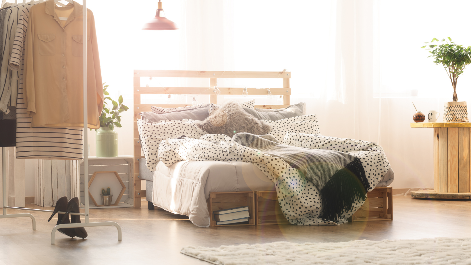 studio apartment with clothes rack next to bed