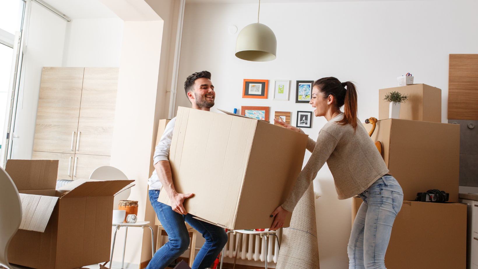 man and woman carrying moving boxes